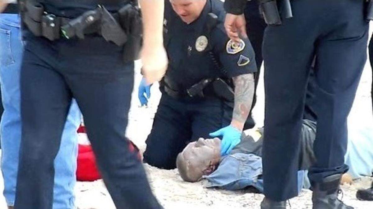 This is an image taken from a YouTube video of the police takedown at South Beach. Charles Eimers is in the sand surrounded by police.