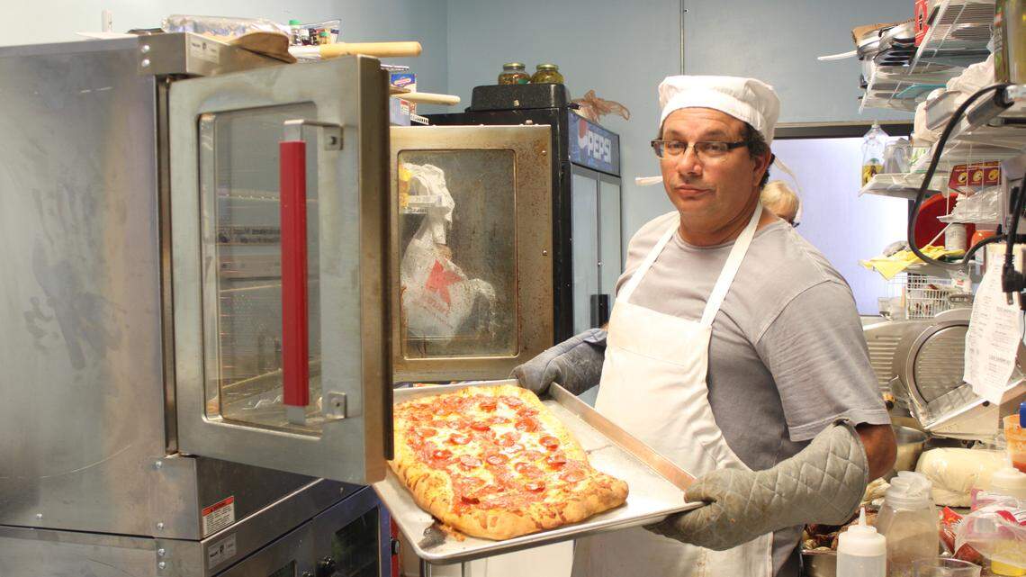 Rich Wells removes a fresh-baked pizza from the oven at Baricci Cafe, which recently opened in Marathon.