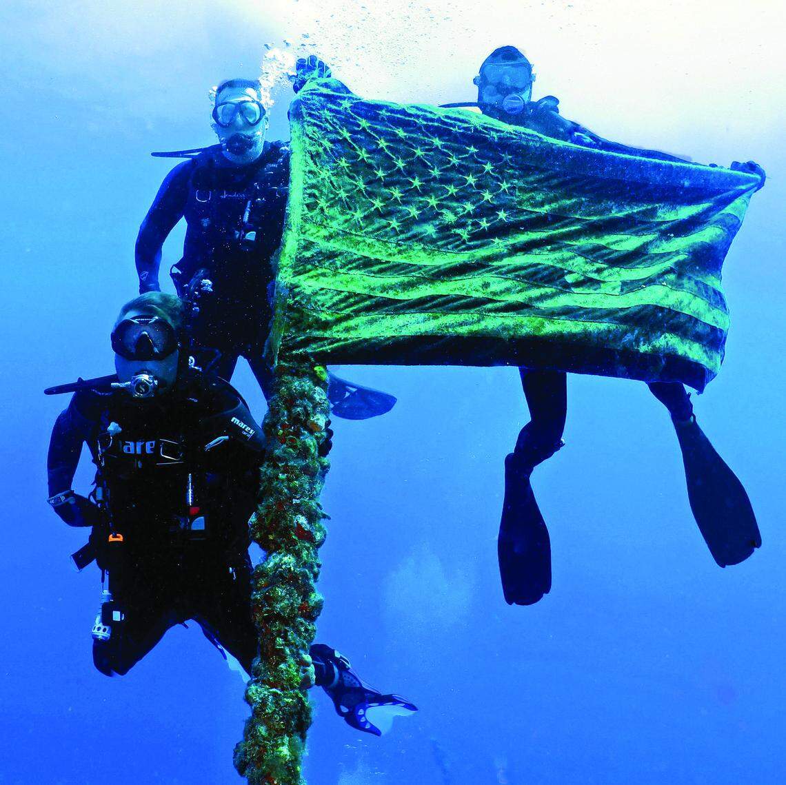 Divers hold the American flag atop the Spiegel Grove.