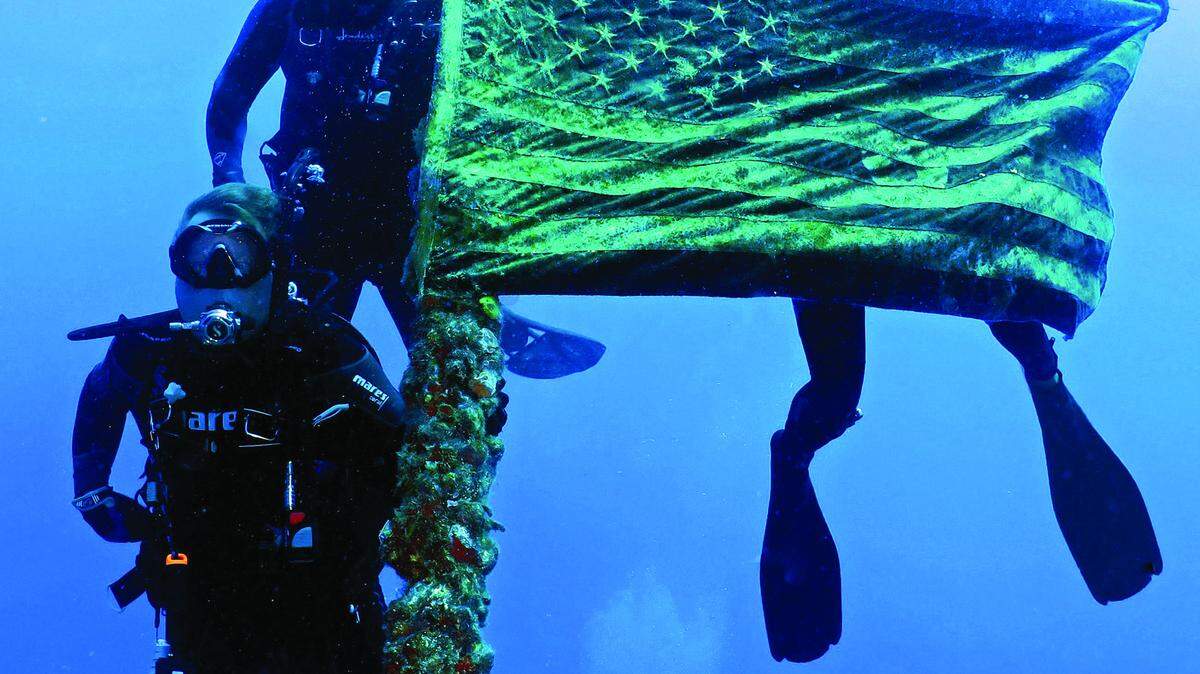 Divers hold the American flag atop the Spiegel Grove.