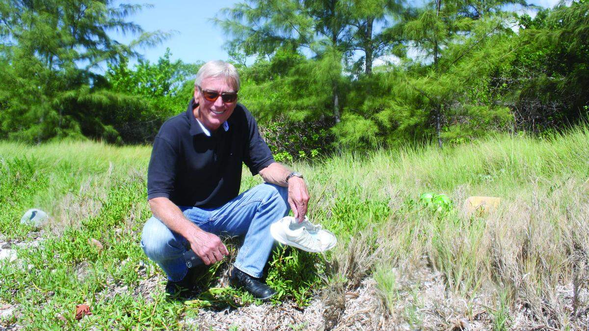 Bert Vorstman, owner of an 8-acre oceanfront property on the Old Highway at mile marker 83, picks up a discarded sneaker, one of many pieces of debris and litter strewn about on his lot.