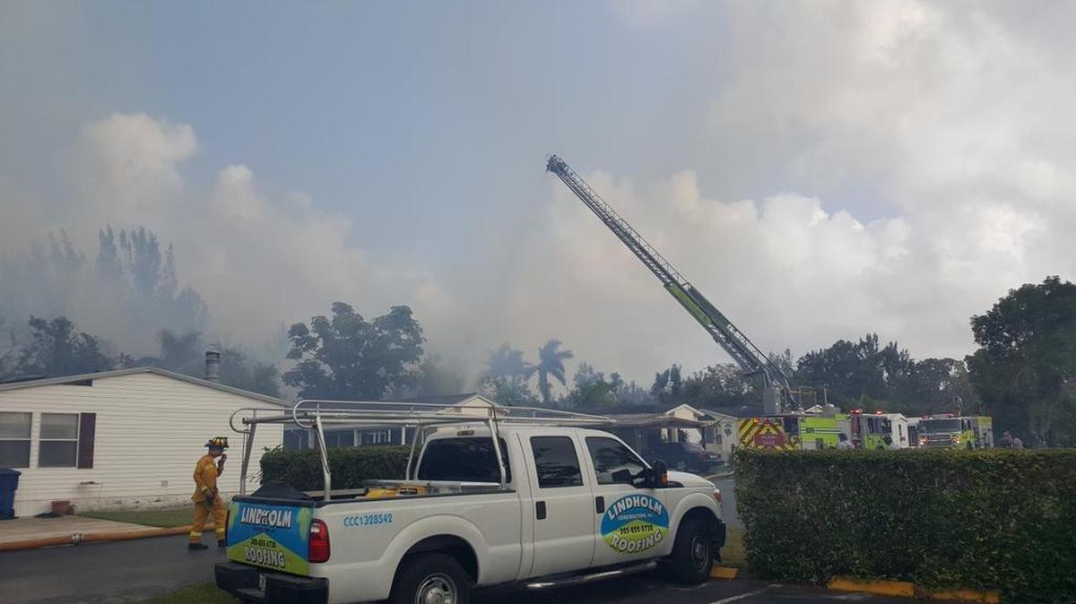 Miami-Dade Fire Rescue firefighters spray homes at the Gateway Estates trailer park in Homestead Monday to prevent a nearby brush fire from destroying homes there.