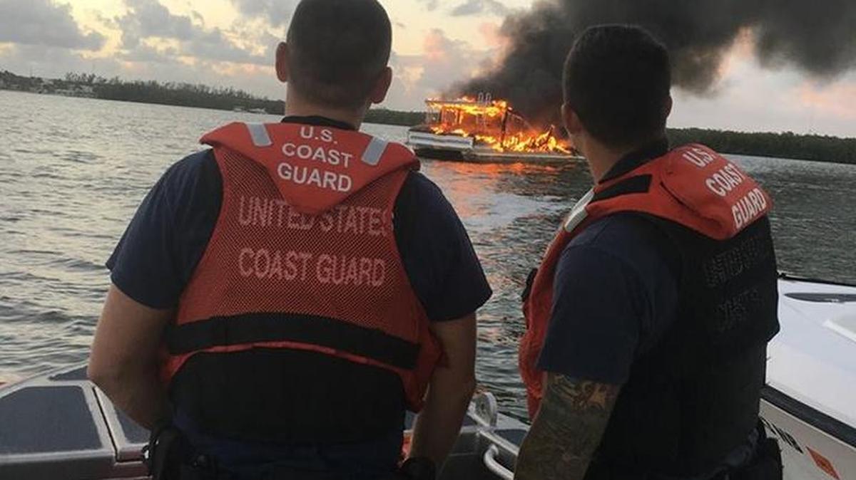 U.S. Coast Guard crewman watch the smoldering remains of a houseboat in Tarpon Basin off Key Largo.