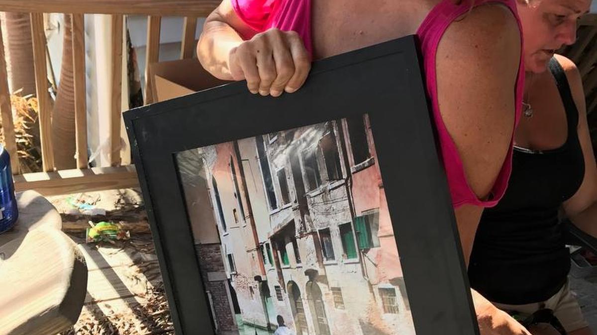 Donna Martini holds a framed photograph her friend, professional photographer Heather Allen, shot of Venice, Italy. Allen’s Sea Breeze RV and Marina home was destroyed by Hurricane Irma.