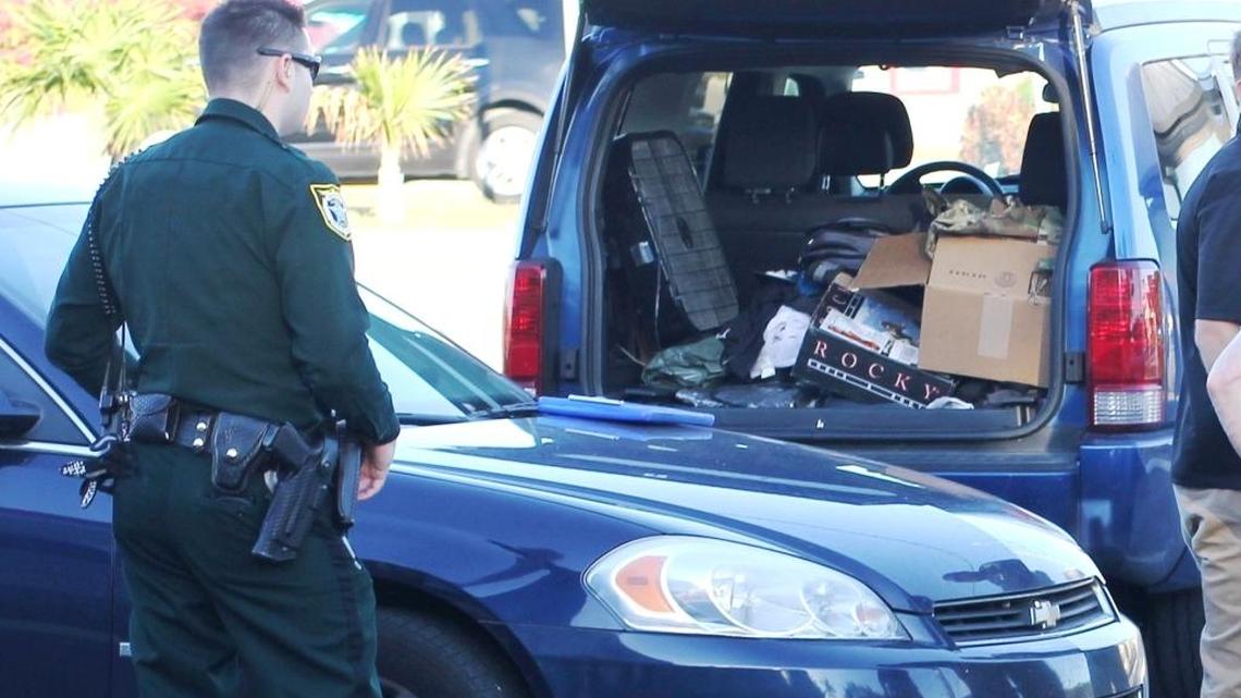A Monroe County Sheriff’s Office deputy stands behind a blue Dodge SUV in the Burger King parking lot at mile marker 99 in Key Largo Sunday. At least one person in the vehicle is wanted on federal explosives charges in Tampa.