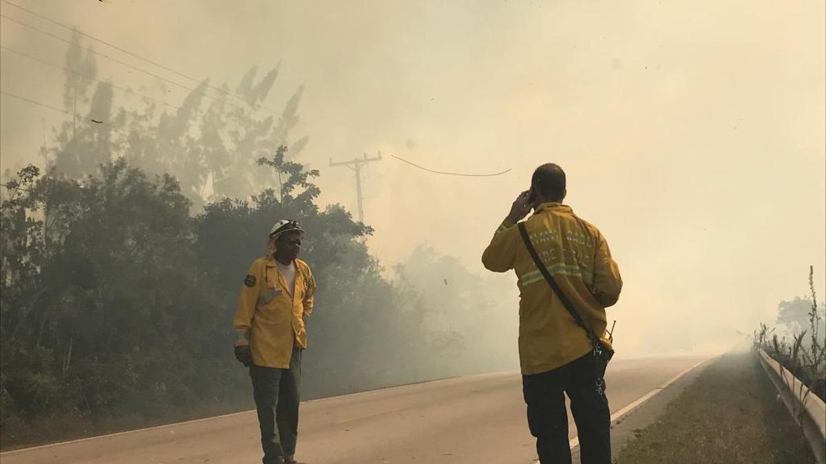 Terrance Gadson, Florida area supervisor for the Florida Forest Service, talks to a Miami-Dade Fire Rescue firefighter as a brush fire crosses from one side of Card Sound Road to the other Wednesday, Feb.14. The Department of Environmental Protection is planning a prescribed burn at Curry Hammock State Park near Marathon, in part, to avoid similar brush fires. .