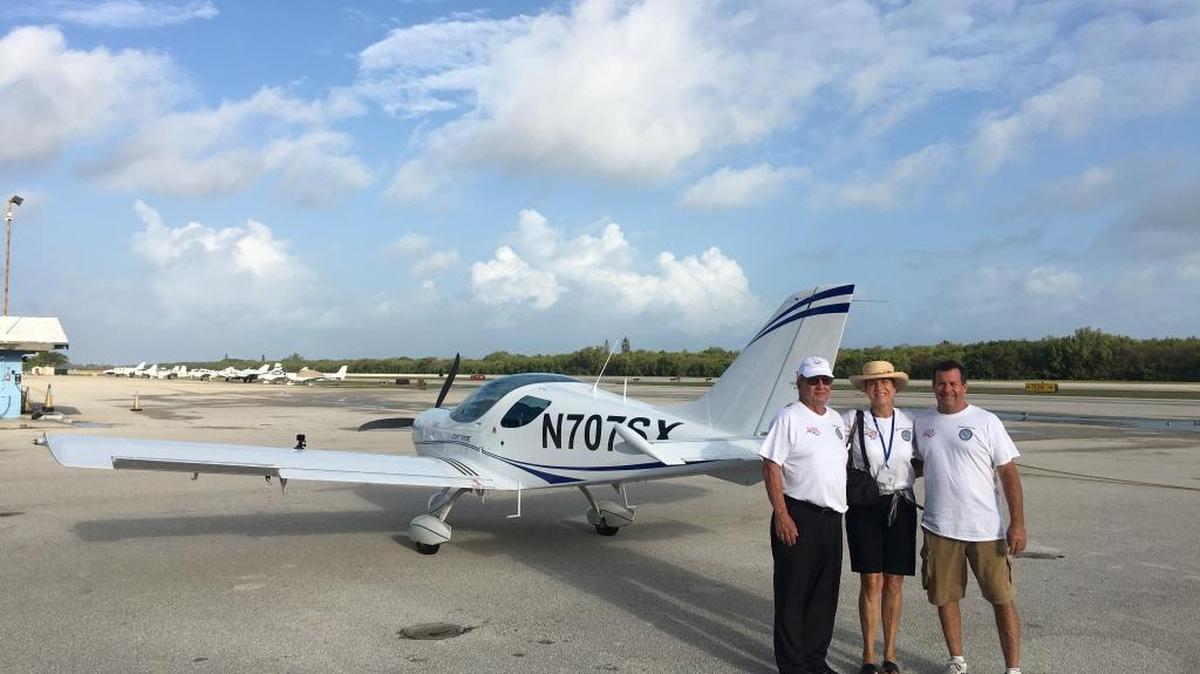 Thomas Schrade (left), Erin Porter and pilot Bob Harris pose in front of a Czech Sport Cruiser Friday before takeoff.